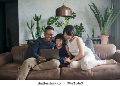 Young Asian Family Looking At The Laptop Together At Home.