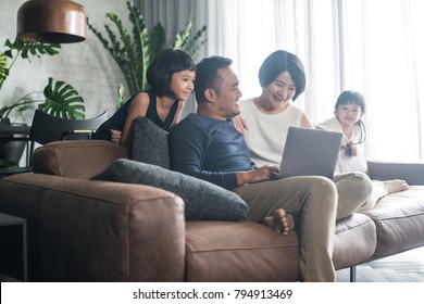 Young Asian Family Looking At The Laptop Together At Home.