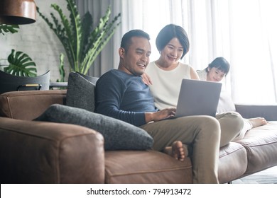 Young Asian family looking at the laptop together at home.
