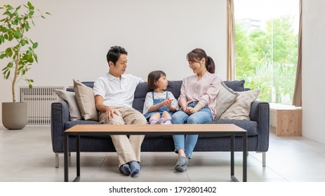 Young Asian Family Relaxing At Modern Living Room