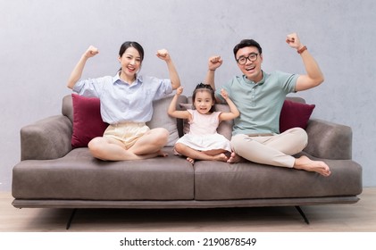 Young Asian Family Sitting On Sofa