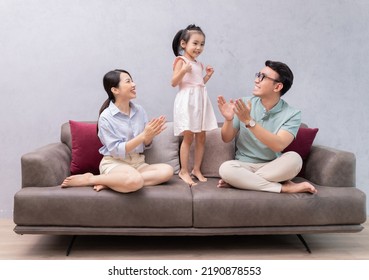 Young Asian Family Sitting On Sofa