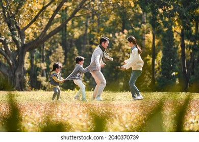 young asian family with two children having fun playing game outdoors in park