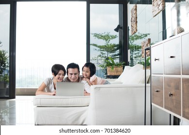 Young Asian Family Using A Laptop Together At Home.