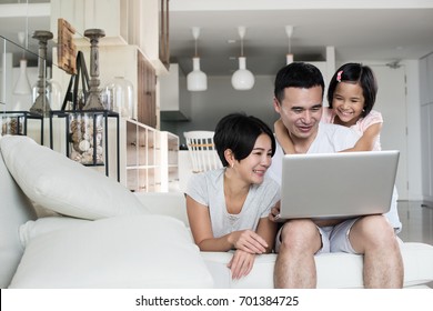 Young Asian Family Using A Laptop Together At Home.