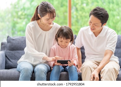 Young Asian Family Using Smart Phone At Living Room