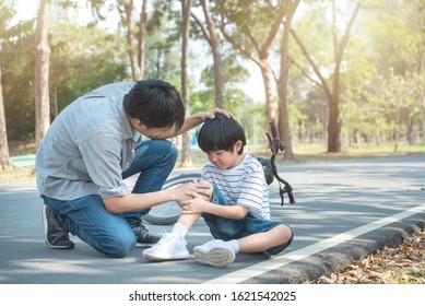 Young Asian Father Of Dad Calms Son That Fell From The Bike And He Get Injury On Knee And Leg While Have Weekend Leisure In Public Park,accident Can Happen Everywhere And Every Time.