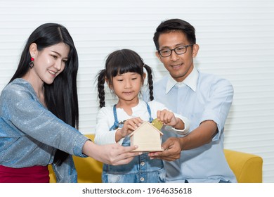 Young Asian Father, Mother And Their Cute Little Daughter Saving Money With Bitcoin At Home Concept