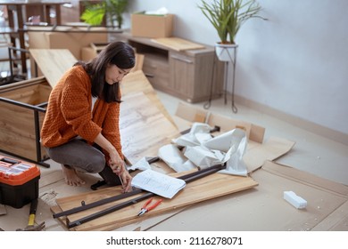 Young Asian Female Assembling Furniture On Her Own