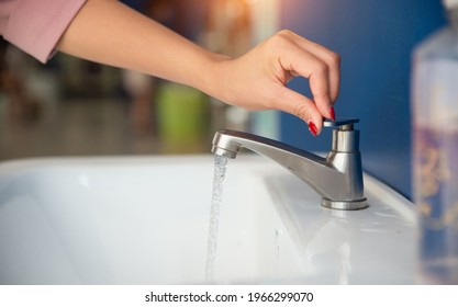 Young Asian female beautiful hands with red nail polish open or close modern water tap, washing hand. Modern stainless faucet over sink in bathroom. Hygiene concept hand detail. Save water concept - Shutterstock ID 1966299070