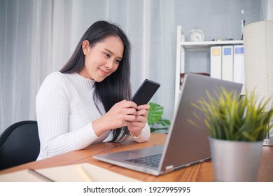 Young Asian Female College Student Studying Online Class Using Mobile Smartphone App Contact Computer Laptop Browsing Internet Online Education Learning, Happy Smiling Home Quarantine Modern Office