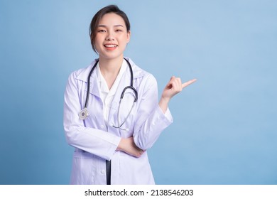 Young Asian Female Doctor Standing On Blue Background