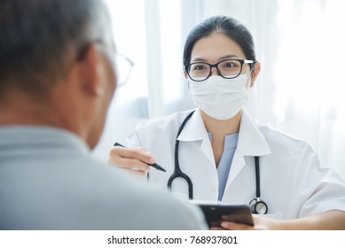 Young Asian Female Doctor wear eyeglasses, surgical mask talking giving advice to Elderly man patient about pandemic virus in medical room at hospital. Disease, Illness, Flu. BeH3althy
 - Shutterstock ID 768937801