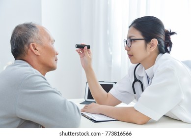 Young Asian Female Doctor Wear Glasses Checking Senior Man Patient Eyes With Flashlight In Medical Room At The Hospital. Cataract, Glaucoma, Lasik.