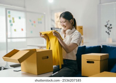 Young asian female entrepreneur is unpacking clothes in her startup office, excited to get her new business up and running - Powered by Shutterstock