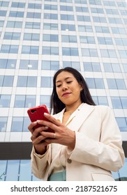 Young Asian Female Executive Chatting With A Phone In The Streets Of A Financial District. Businesswoman