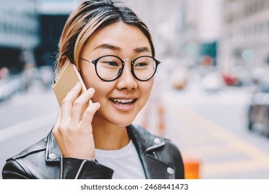 Young asian female in eyewear having mobile conversation while walking in big city center, crossing road,chinese hipster girl talking with taxi service operator discussing details standing on avenue - Powered by Shutterstock