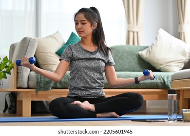 Young Asian Female Lifting Dumbbell And Working On Her Biceps.