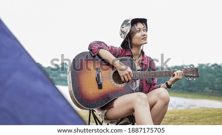 young Asian female playing guitar at camping