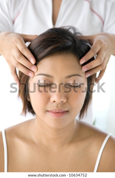 Young Asian female\
receiving gentle head massage as part of holistic therapy treatment\
in spa lifestyle