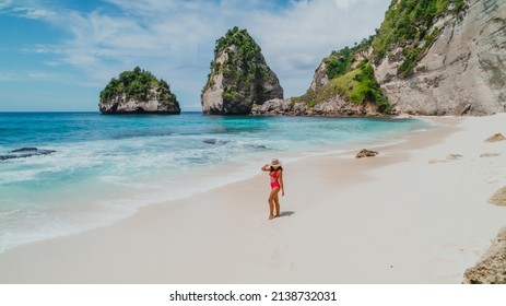 Young asian female in a red bikini on a tropical white sand beach with turquoise water at Diamond Beach in Nusa Penida Bali Indonesia