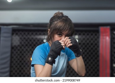 A young Asian female strawweight boxer poses for the camera while showing the proper fighting stance before throwing a punch. - Powered by Shutterstock