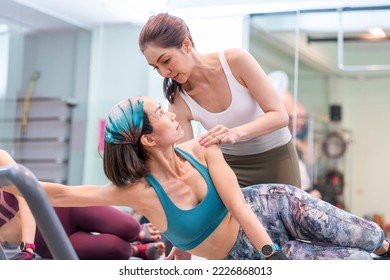 Young asian female trainer training senior woman doing pilates stretching with pilates bed equipment in class at gym. - Powered by Shutterstock