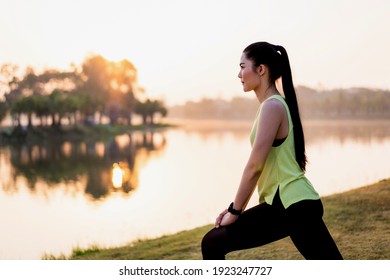 A young Asian female workout before a fitness training session at the park under sunlight in the morning. Healthy young woman runner warming up outdoors before jogging. Sport and recreation