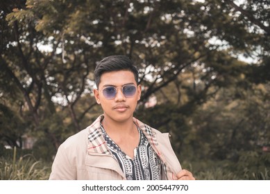 A Young Asian Gangster In Blue Semi Opaque Shades Walking Around At The Park.