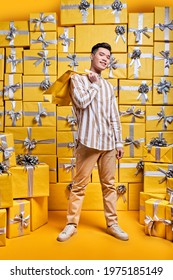 Young Asian Gentleman Holding Some Shopping Bags, Going To Celebrate Birthday, Congratulate, Posing Around Gifts, Looking At Camera With Happy Facial Expression