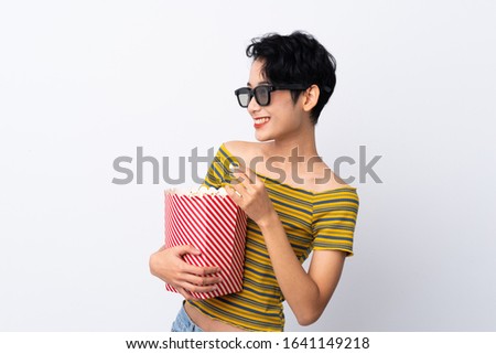Young Asian girl with 3d glasses and holding a big bucket of popcorns