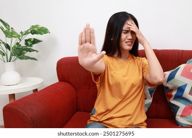 Young asian girl covering eyes showing stop gesture, sitting on sofa, tired of tv shows, series - Powered by Shutterstock