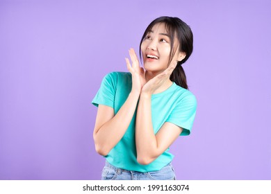 Young asian girl in cyan shirt posing on purple background
