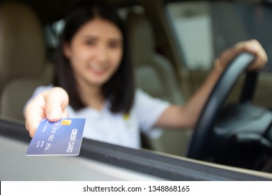 Young Asian Girl Driving Car Hand Holding Credit Card Payment For Gasoline At Petrol Station. Happy Woman Car Owner Paying Fuel Pump With Credit Card, Customer Mileage Point Loyalty Reward Concept.