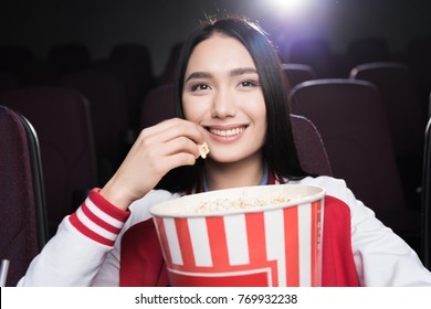 Young Asian Girl Eating Popcorn And Watching Movie In Cinema