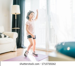 Young asian girl exercise watching online video on TV and doing fitness exercise dance at home.Distant training with personal trainer,Home Social distance or self-isolation, Online education concept