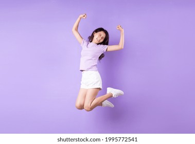 Young Asian Girl Jumping Up On Purple Background