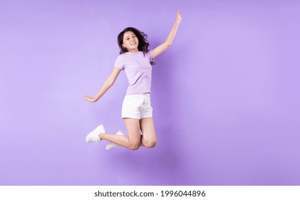 Young Asian Girl Jumping Up On Purple Background