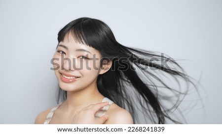 Young Asian girl with long black hair blowing in the wind.