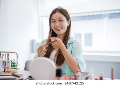 Young Asian girl makeup artist Professional Woman blogger vlogger is showing cosmetics products with recording video Beauty influencer asian girl video online marketing - Powered by Shutterstock