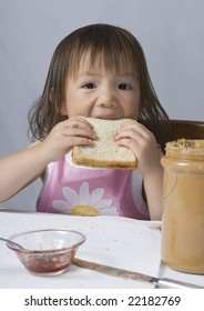 A Young Asian Girl Making A Peanut Butter And Jelly Sandwich