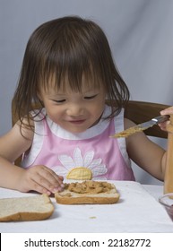 A Young Asian Girl Making A Peanut Butter And Jelly Sandwich