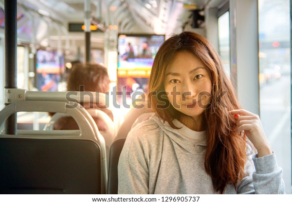 Young Asian\
girl on the bus sitting and\
smiling.