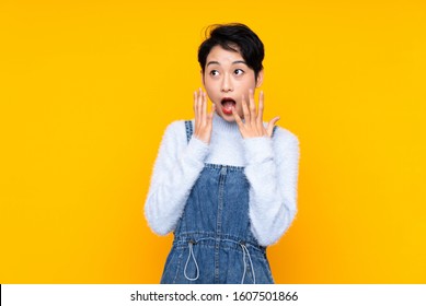 Young Asian girl in overalls over isolated yellow background with surprise facial expression - Shutterstock ID 1607501866