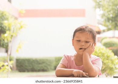 Young Asian girl in pink shirt feeling bored on chair. Depressed girl sits on chair with sad mood. - Shutterstock ID 2366935841