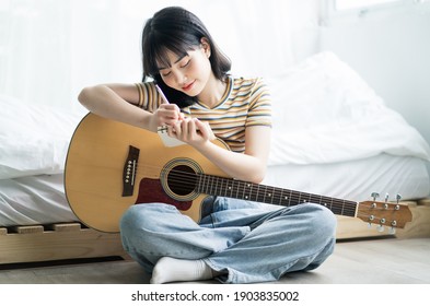 Young Asian girl is practicing guitar at home and composing music
 - Powered by Shutterstock