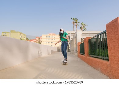 Young asian girl riding skateboard while wearing protective face mask - Concept of coronavirus lifestyle - Powered by Shutterstock