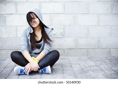 Young asian girl sitting in urban background