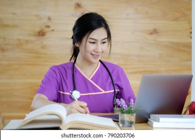 Young Asian Girl, Student Of Medicine Using Laptop And Researching Books At Desk.