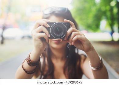 Young asian girl taking photo outdoors with digital camera. Selective focus at lens, unrecognizable person. Young female tourist having fun in summer park. Lifestyle portrait, soft toned